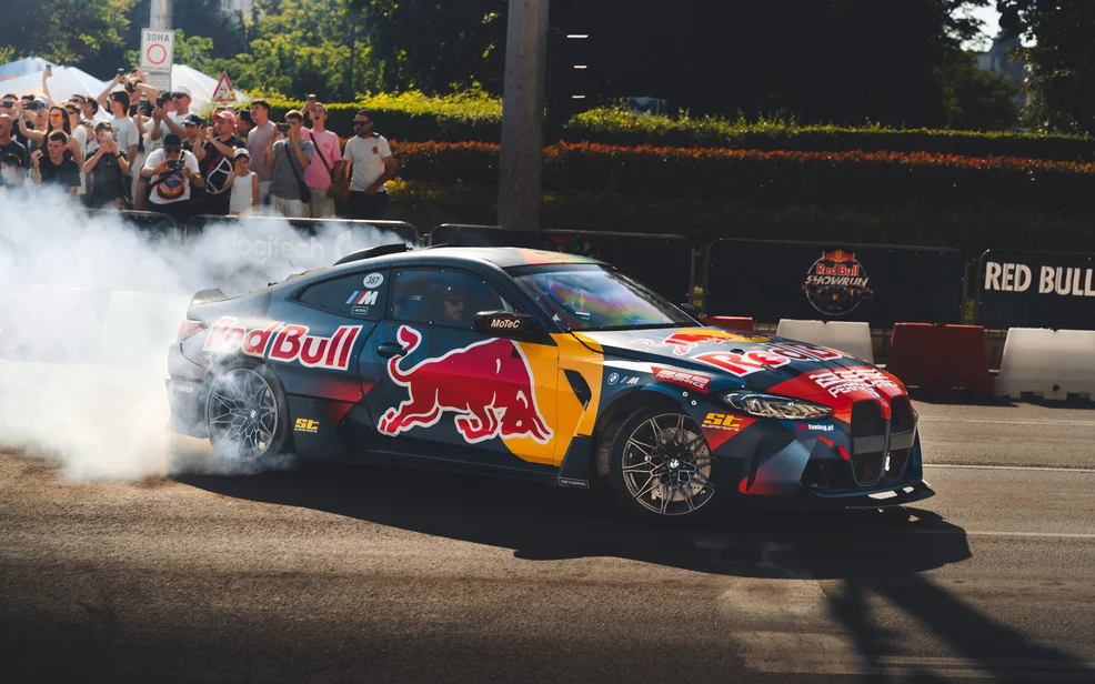 Автомобил в цветовете на Red Bull дрифтира в облак дим