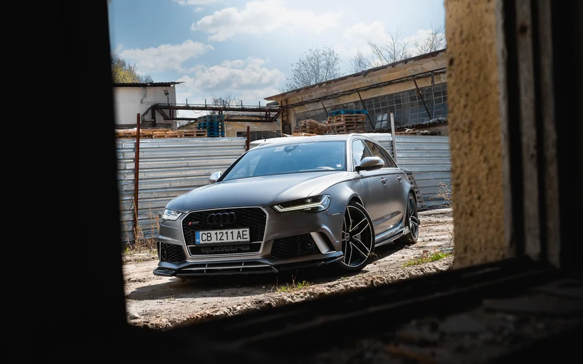 Сив Audi RS6, видян през отвор в сграда