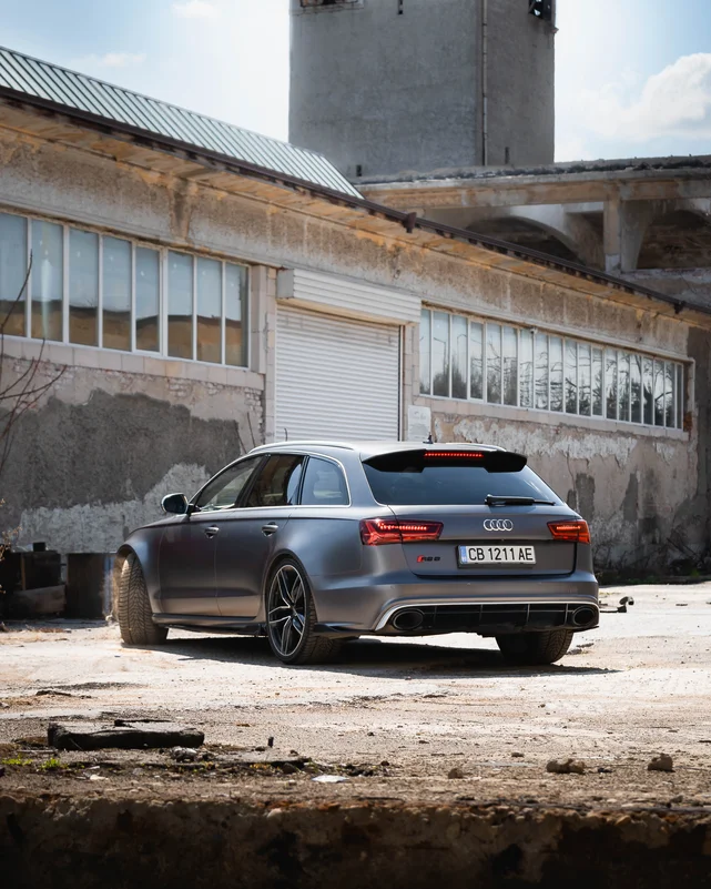 Сив Audi RS6 Avant пред изоставена индустриална сграда