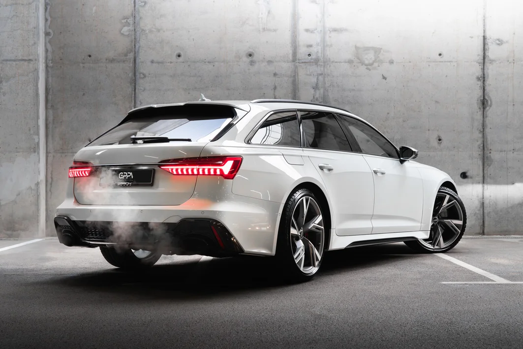 Бял Audi RS6 Avant отзад в бетонен паркинг, с дим от ауспуха