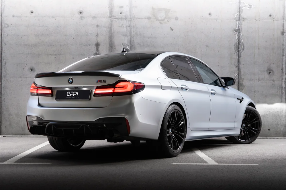 Бяло BMW M5 отзад в бетонен паркинг