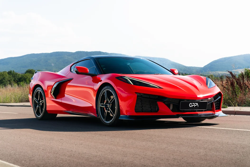 Червен Chevrolet Corvette на път с планина зад него