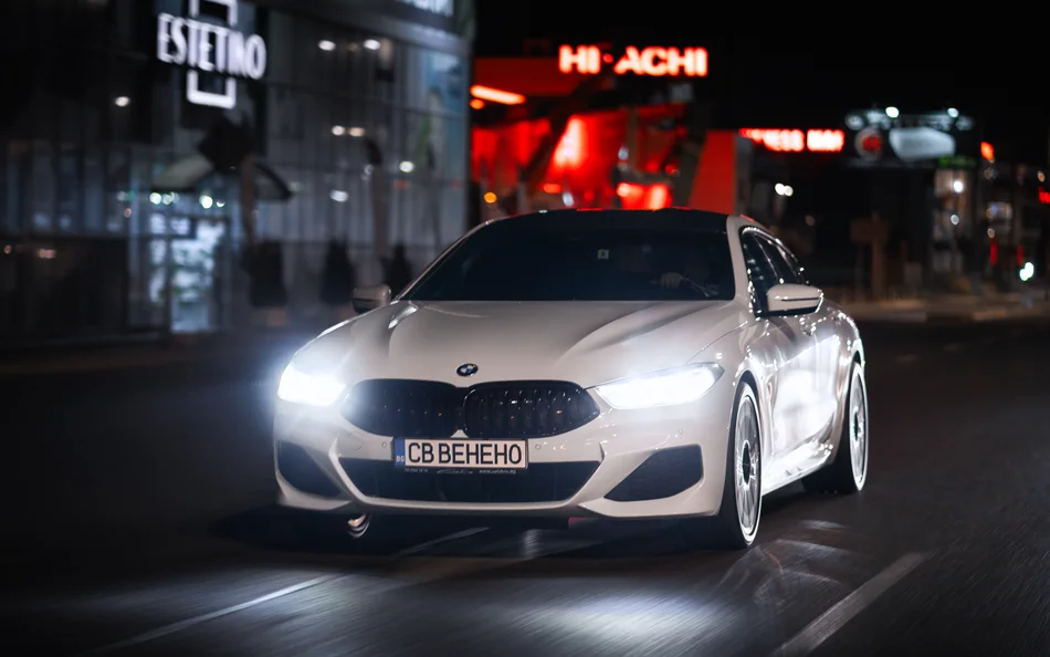Бяло BMW отпред нощем на градска улица