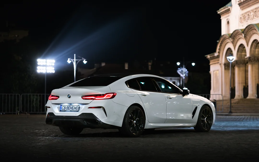 Бяло BMW нощем пред класическа сграда