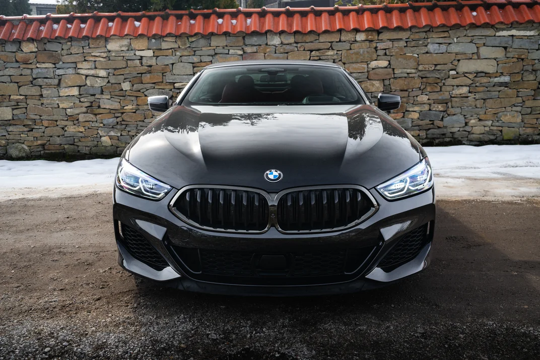 Черно BMW отпред на фона на каменна стена и сняг